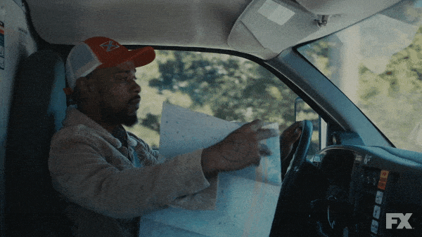 A gif of a man trying to read a map while driving.